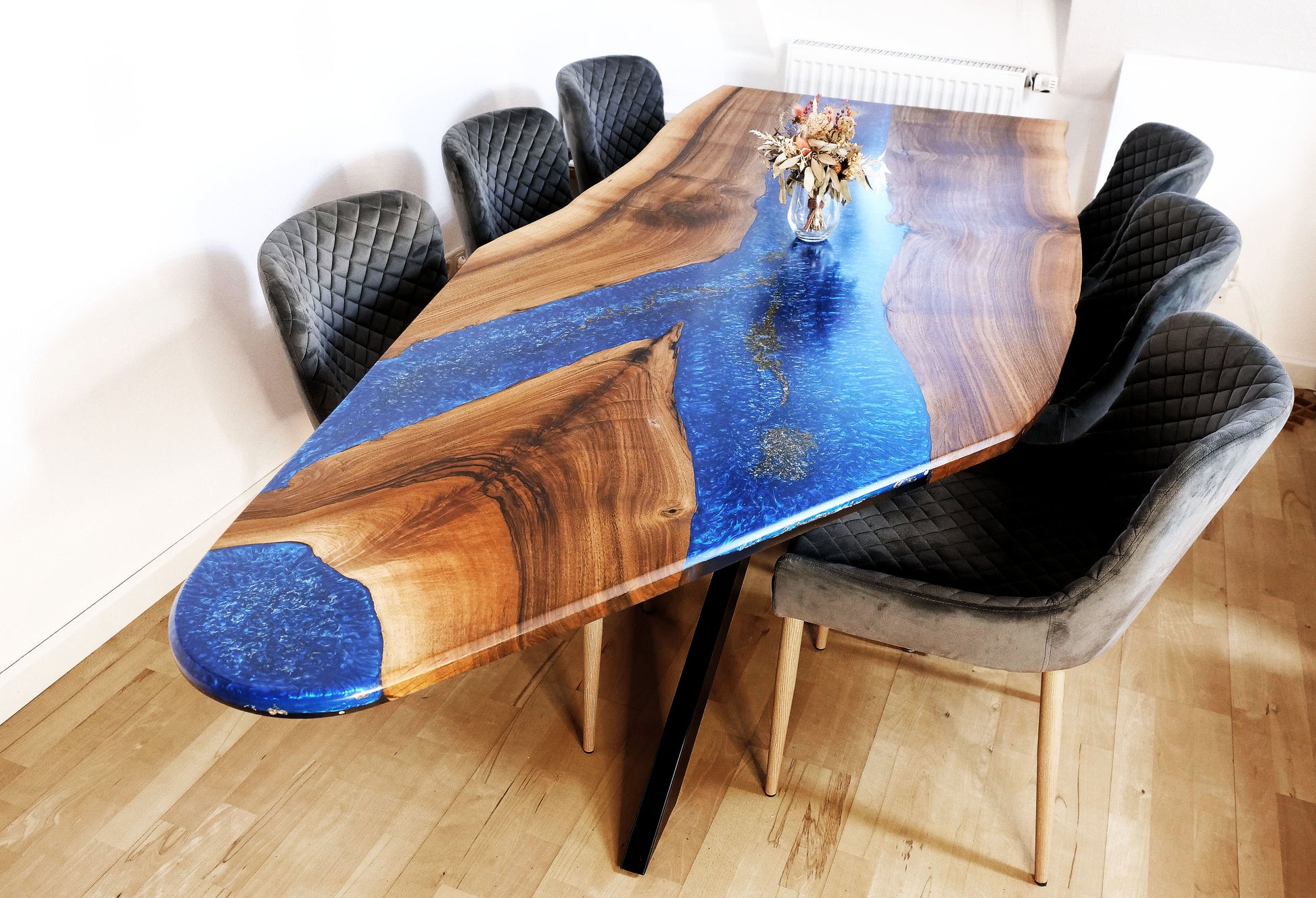 Blue Ember Esstisch aus massivem Nussbaumholz und tiefblauem Epoxidharz – schräg von vorne fotografiert. Handgefertigtes Designprodukt mit goldenen Akzenten und organischer Tischkante.