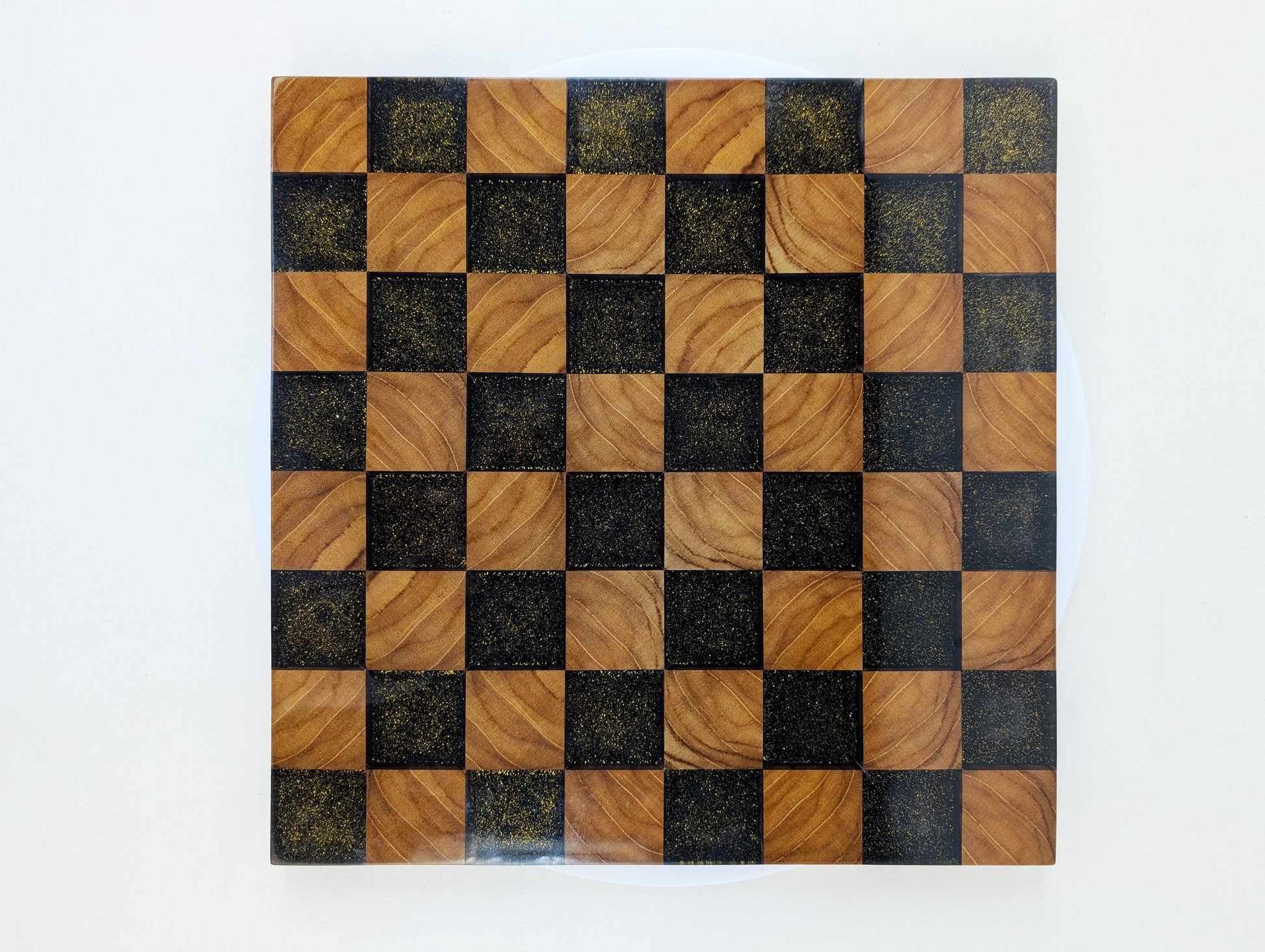 Vogelperspektive auf das Golden Gambit Schachbrett – quadratische Spielfläche aus Edelholz und Epoxidharz mit goldenen Akzenten. Hochwertige Handwerkskunst im FIDE-Format.