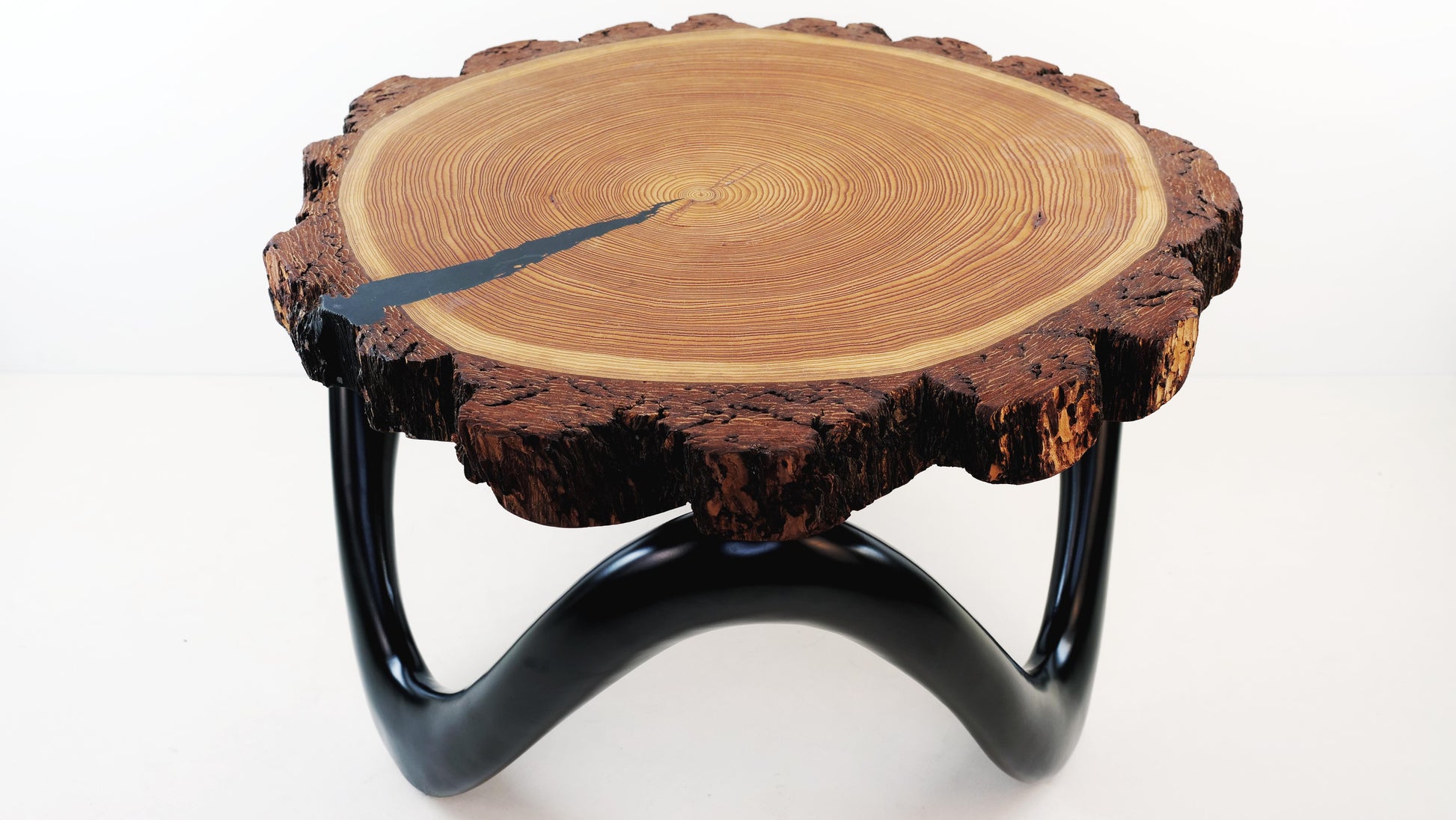 Schräger Blick auf den Nordic Wave Couchtisch mit dreibeinigem Untergestell in Seidenglanz-Schwarz – ein handgefertigtes Unikat aus Massivholz und Kunststoff, stilvoll und funktional.