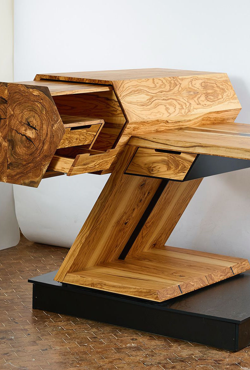 Terra Vero Massivholz-Schreibtisch mit asymmetrischem, pulverbeschichtetem Stahlgestell und edlem Olivenholz, schräg von der Seite aufgenommen – ein Statement moderner Handwerkskunst by Steigerwood.